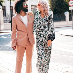 Beautiful fashion woman and her handsome elegant boyfriend in beige suit. Sexy blond model in summer suit clothes. Fashionable smiling couple posing in street Europe. Brutal man and female outdoors